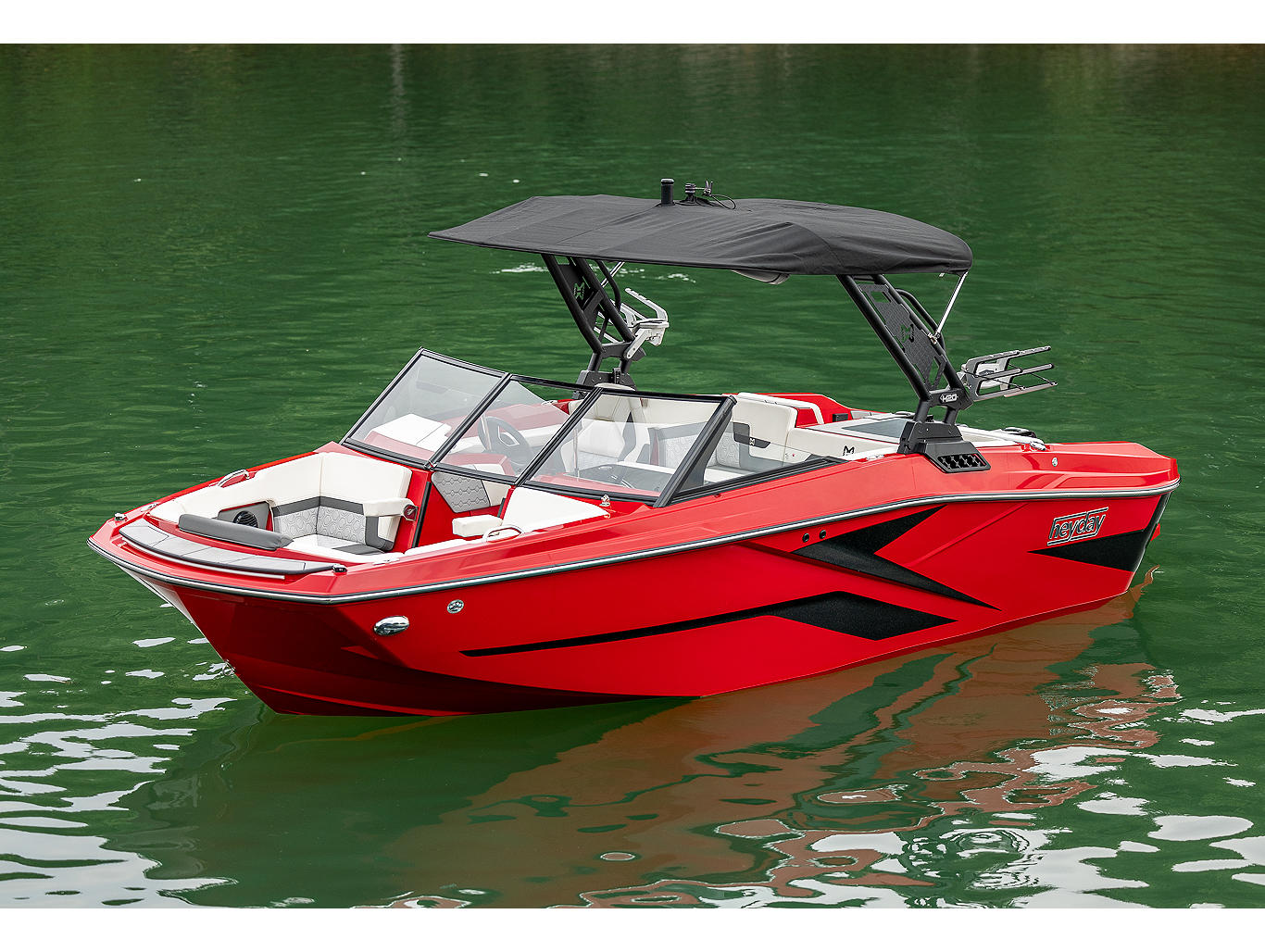 Group of people and dog lounging in a black and blue 2021 Heyday Wake Boat  in calm water.