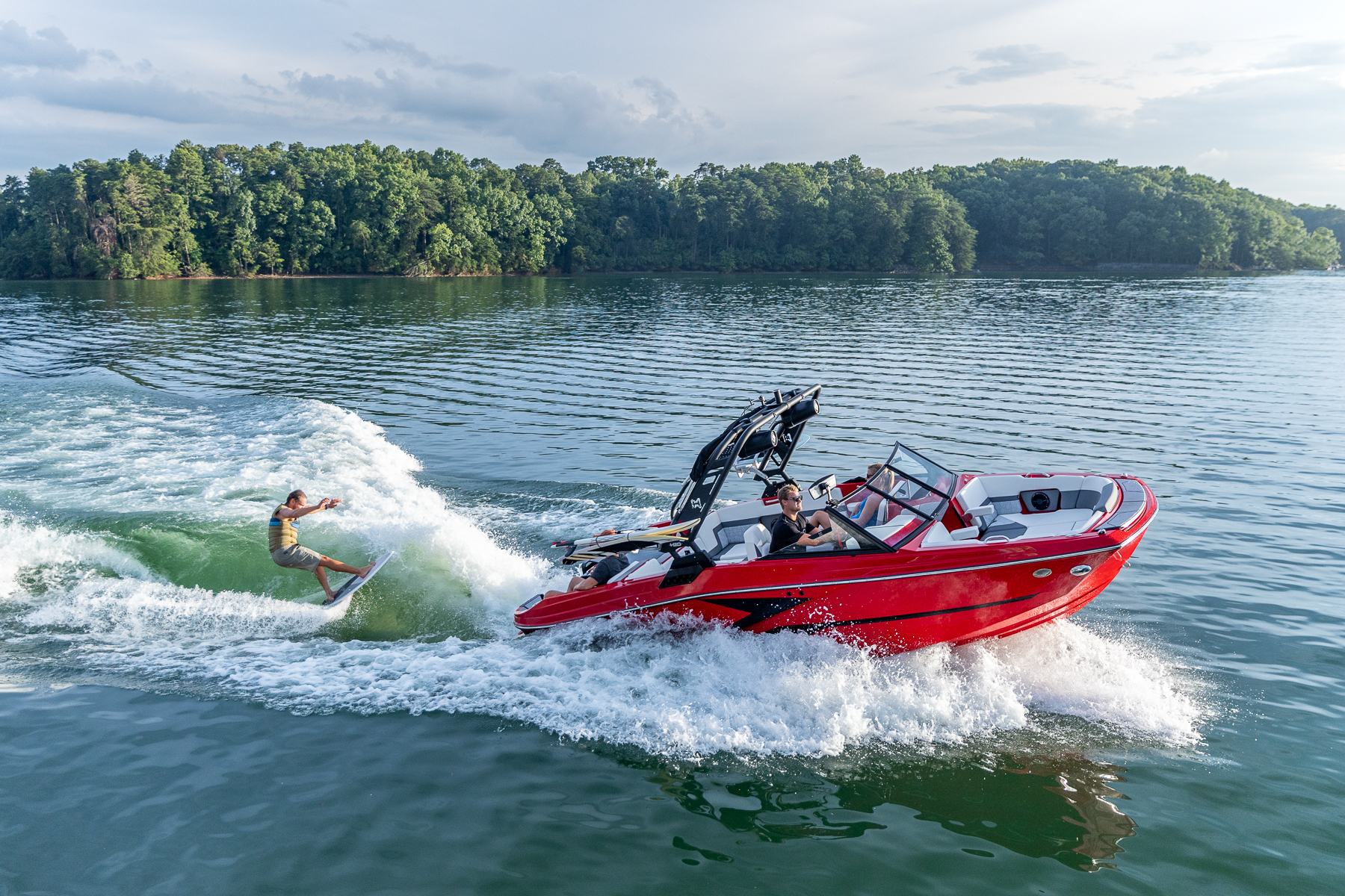 Heyday wake boat on a Texas lake with a wake surfer behind the boat at Fish and Ski Marine